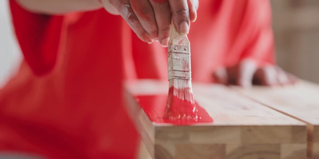 Red paint brushed onto wood